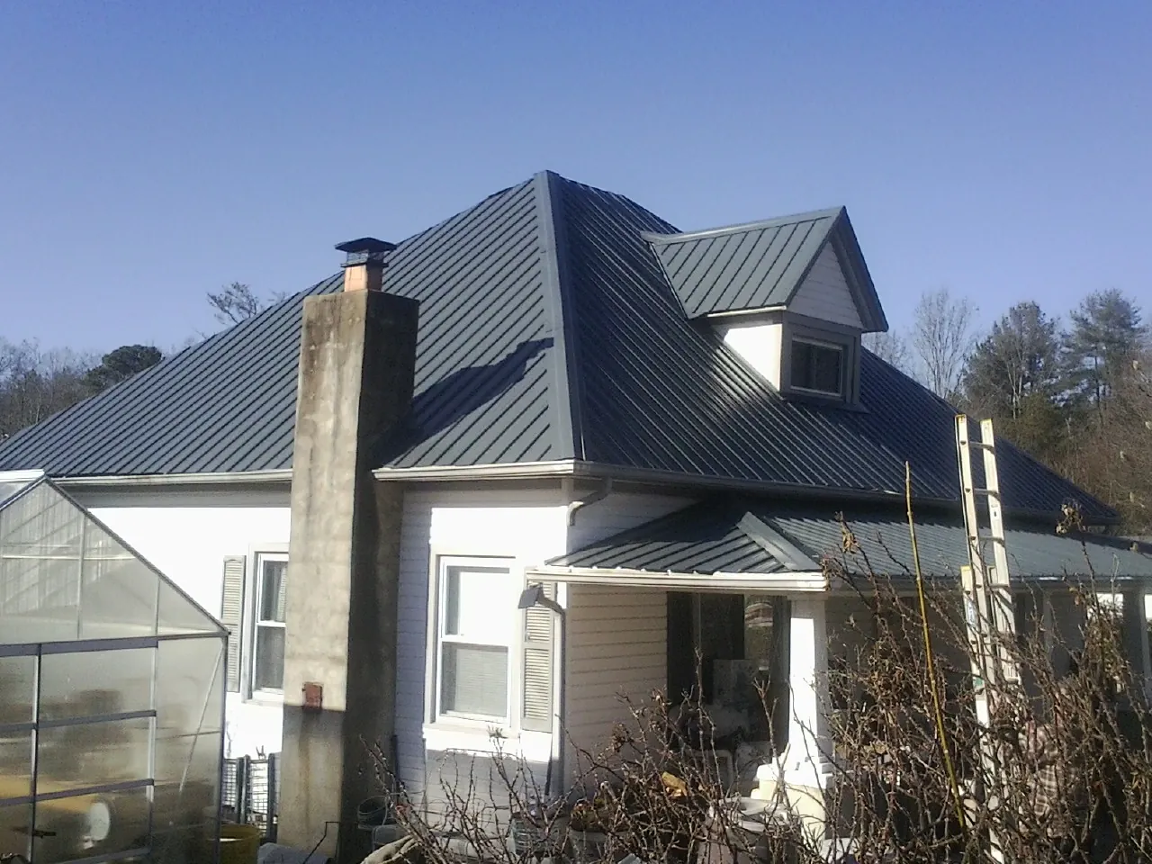 Dark blue standing seam metal roof on a white farmhouse with dormer — Slate & Tile Roof Repair by Roofing Brothers in Big Stone Gap