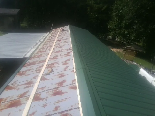 Old rusted panels beside newly installed green metal roofing — Wind Damage Roof Repair by Roofing Brothers in Big Stone Gap