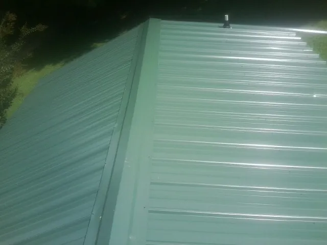 New green metal panels meeting at the ridge of a roof — Flat Roof Repair work by our crew in Big Stone Gap