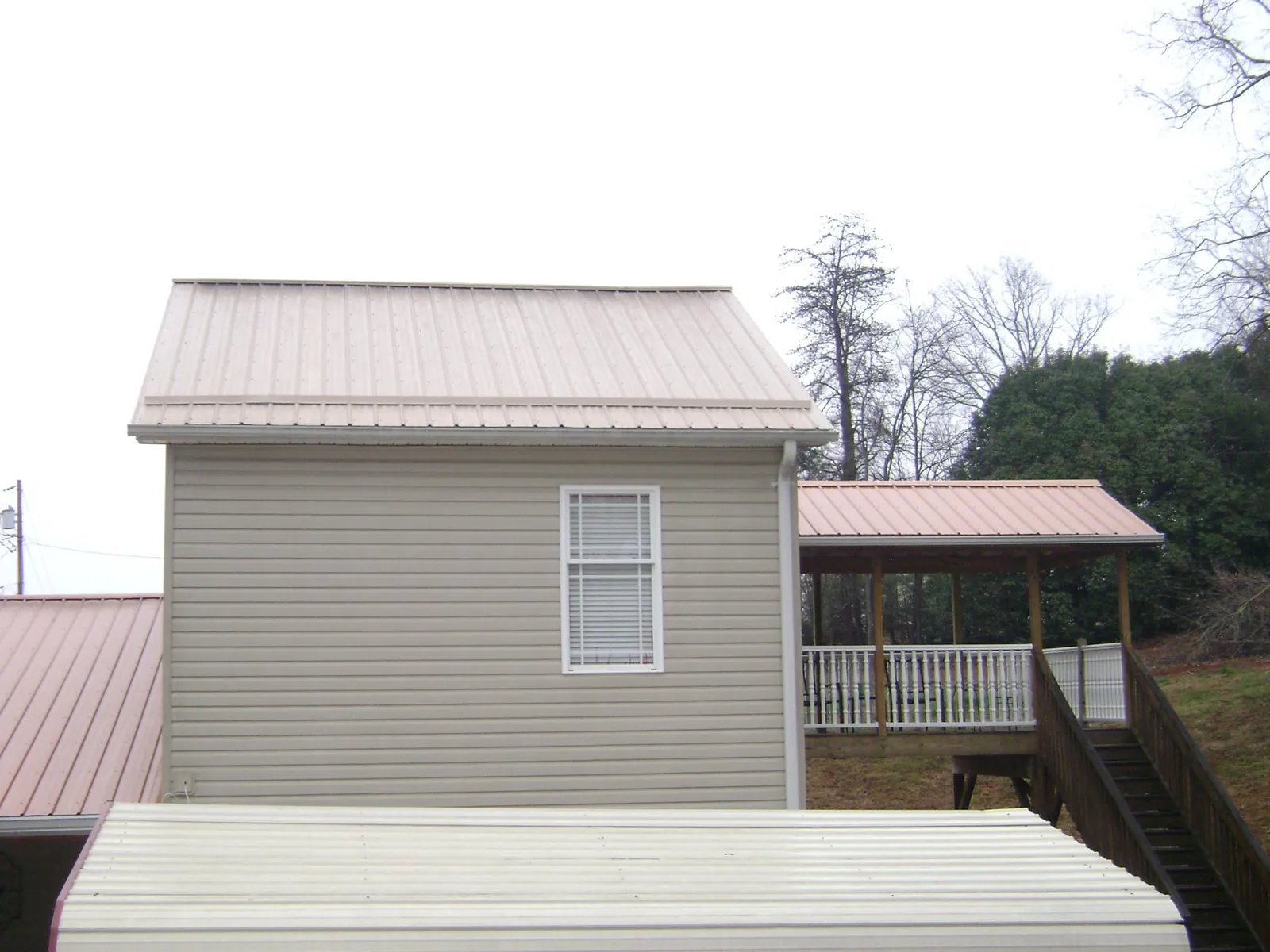 Tan metal roofs on a two story addition and attached porch, from a Roof Replacement job in Big Stone Gap