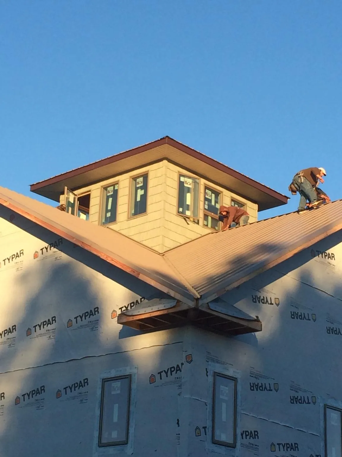Roofers working around a rooftop cupola on a new metal roof at sunset — Roof Waterproofing in Big Stone Gap by Roofing Brothers